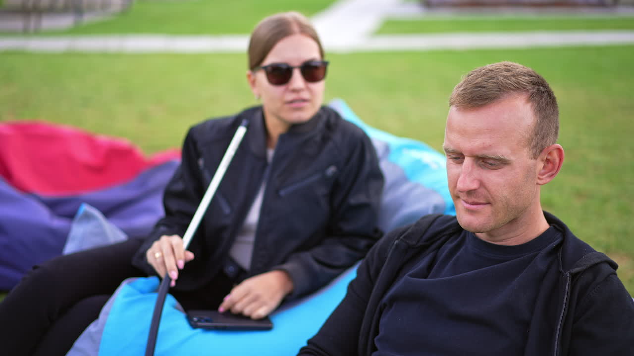 Couple relaxing outdoors with hookah and laptop