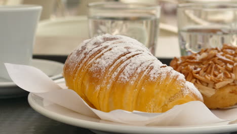 Cerca-De-Un-Delicioso-Croissant-Portugués-Y-Tarta-De-Almendras-En-Un-Plato-En-La-Cafetería