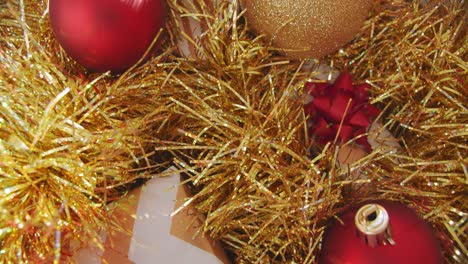 christmas presents with sparkly gold tinsel and warm red baubles, close up