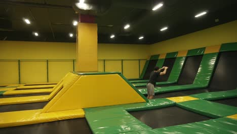un joven atleta masculino entrenando en trampolín profesional, practicando saltos frontales, saltando por encima de las barreras.