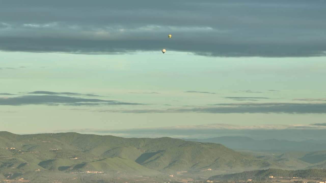 멀리 산 위로 날아가는 다채로운 열기구의 전망