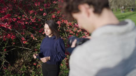 Photographer-and-female-model-in-sunny-day-near-blooming-Chinese-Quince-shrub