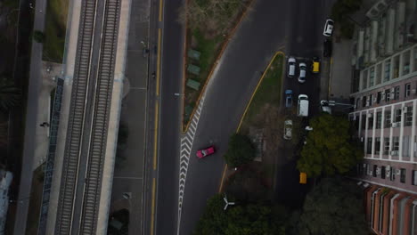 en la bifurcación de la carretera, un coche rojo da la vuelta en la carretera, los ciclistas montan a lo largo del camino para bicicletas, vista superior