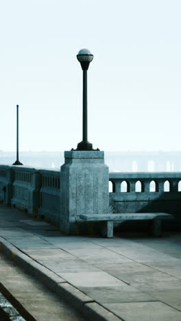 a bench and a street lamp on a foggy bridge