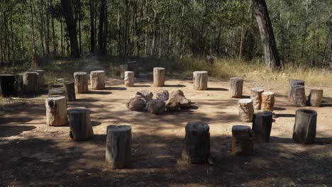 troncos de árboles en círculo con fogata ardiendo en el medio - viaje de 2020 al campamento de hombría - monte byron, queensland - tiro estático completo