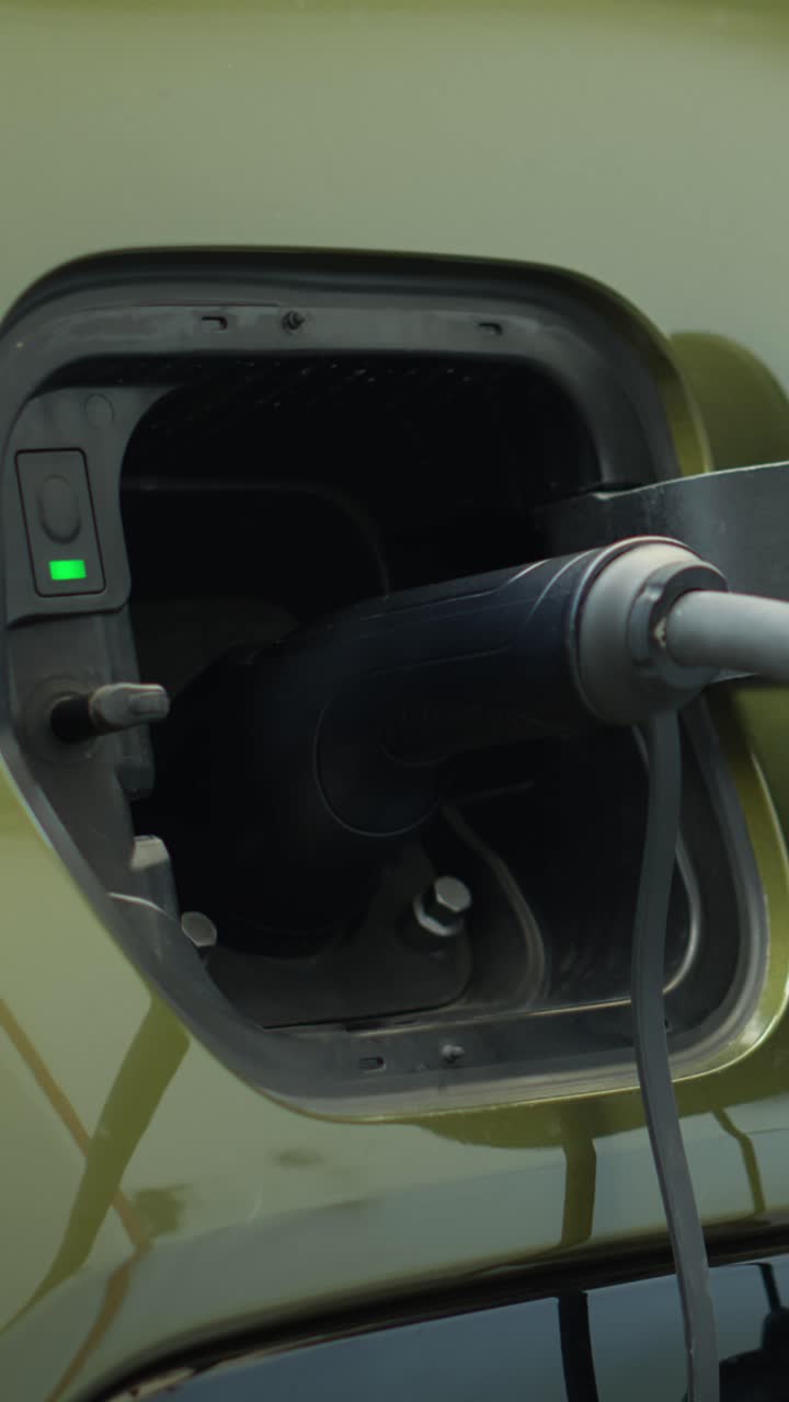 Elektrikli araç şarj portuna elektrik kablosu takan sürücünün yakın çekim dikey videosu
