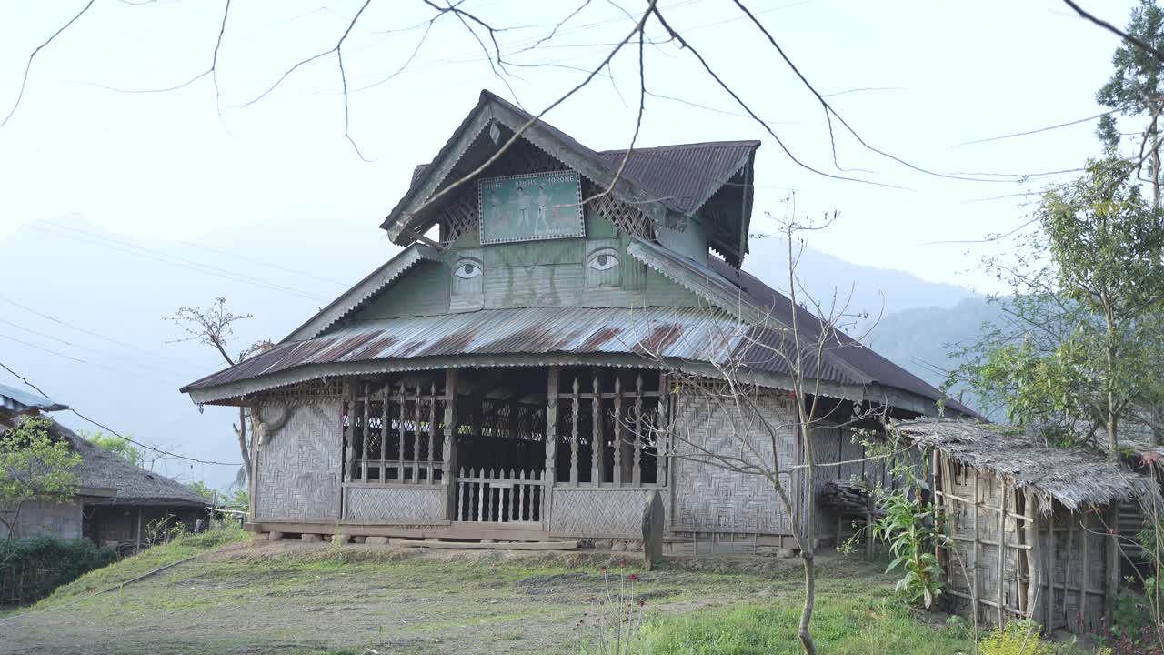 Traditional House with Unique Painted Eyes and Mural in a Rural Mountain Setting