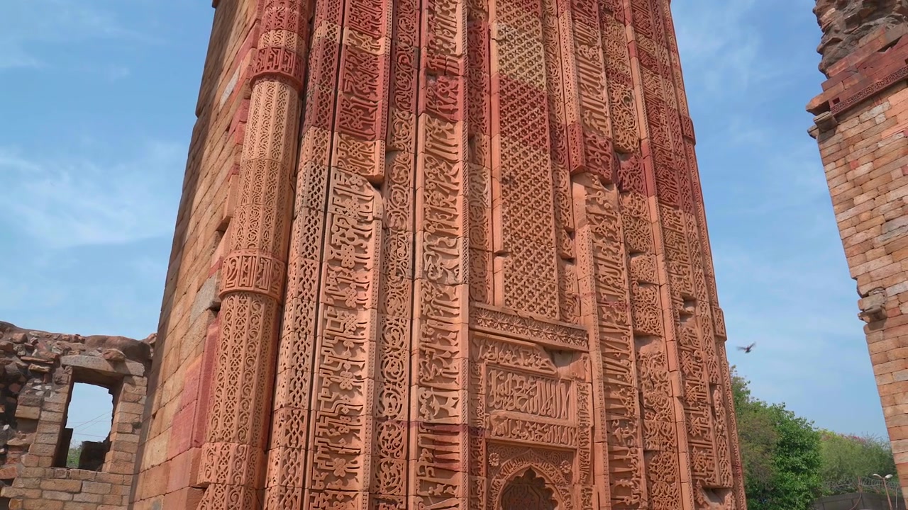 Lavvinkelbillede, der viser den indviklet udskårne røde sandstensfacade af Iltutmishs grav med arabisk kalligrafi ved Qutub-komplekset i New Delhi, Indien.