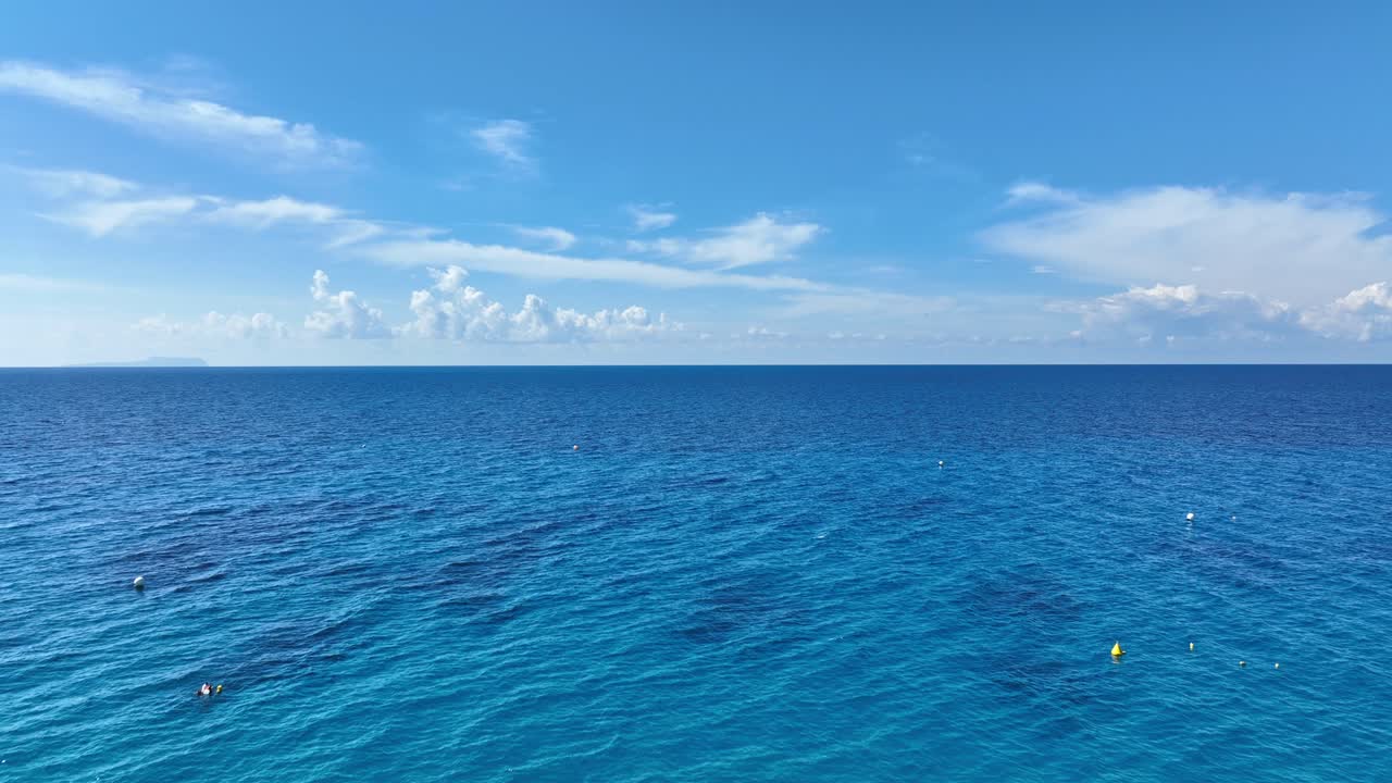 Drone flying over a woman staring at the ocean on a sunny day