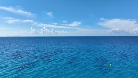 drone flying over a woman staring at the ocean on a sunny day