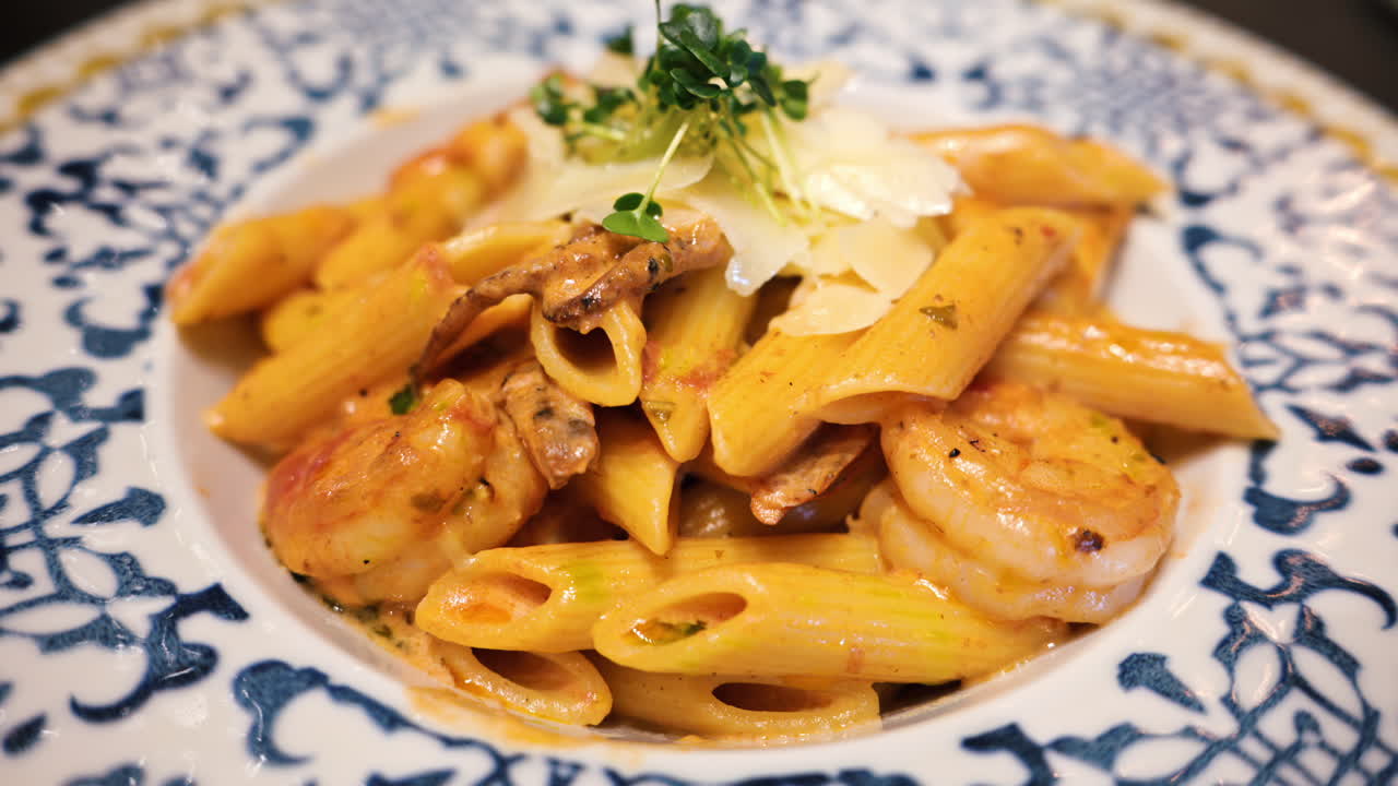 Penne seafood pasta with shrimps and parmesan cheese in a beautiful ceramic plate