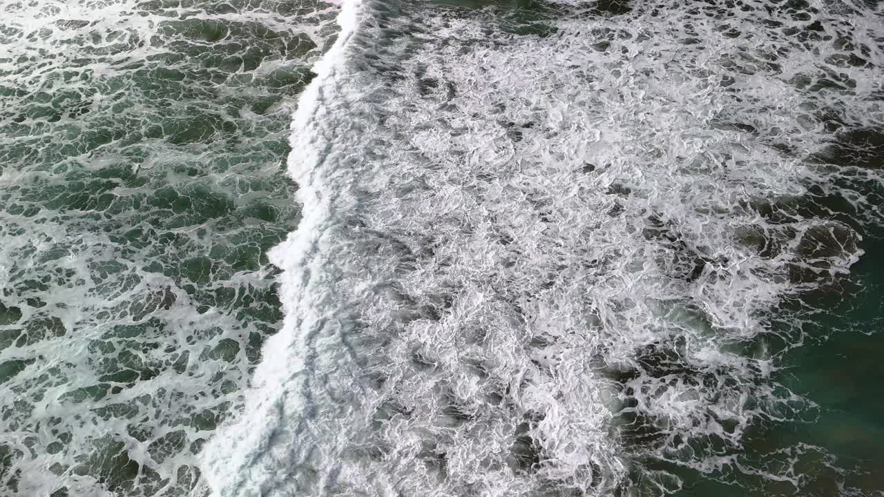 Slow motion, aerial shot following the powerful, crashing waves with white caps