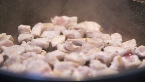 cocinar carne de pollo, asar carne de pollo en una sartén en la cocina por un cocinero italiano