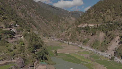 beautiful farming village farms paddy field vegetables growing in mountainous valley in kabayan benguet philippines wide aerial approaching right trucking revealing valley river mountains blue sky