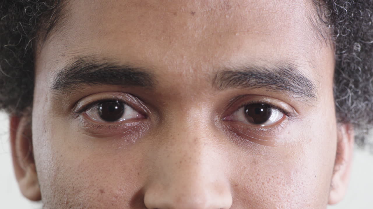 가까운 젊은 혼성 인종 남자가 카메라를 바라보며 눈을 뜨고 눈을 뜨고