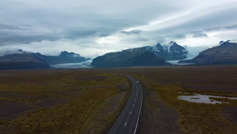 drone tracking a road with a car travelling into the mountains in the distance