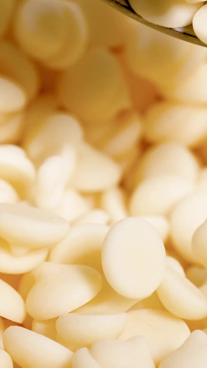 Cucchiaio che raccoglie ripetutamente gocce di cioccolato bianco
