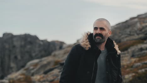 handsome man walking through the mountains, with stunning views of the horizon in the background