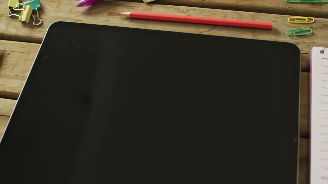 vídeo de una tableta con espacio para copiar y artículos escolares sobre un fondo de madera