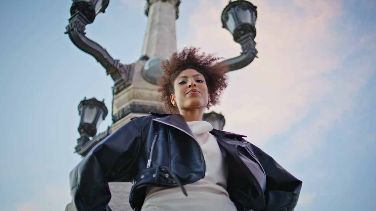 Woman posing historic monument under blue sky bottom view. Stylish lady