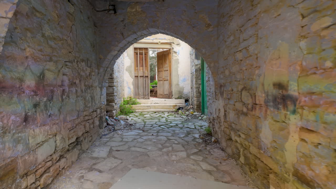 레프카라의 고풍스러운 마당으로 이어지는 돌로 된 아치로, 마을의 전통적인 건축과 조용한 아름다움을 보여줍니다.