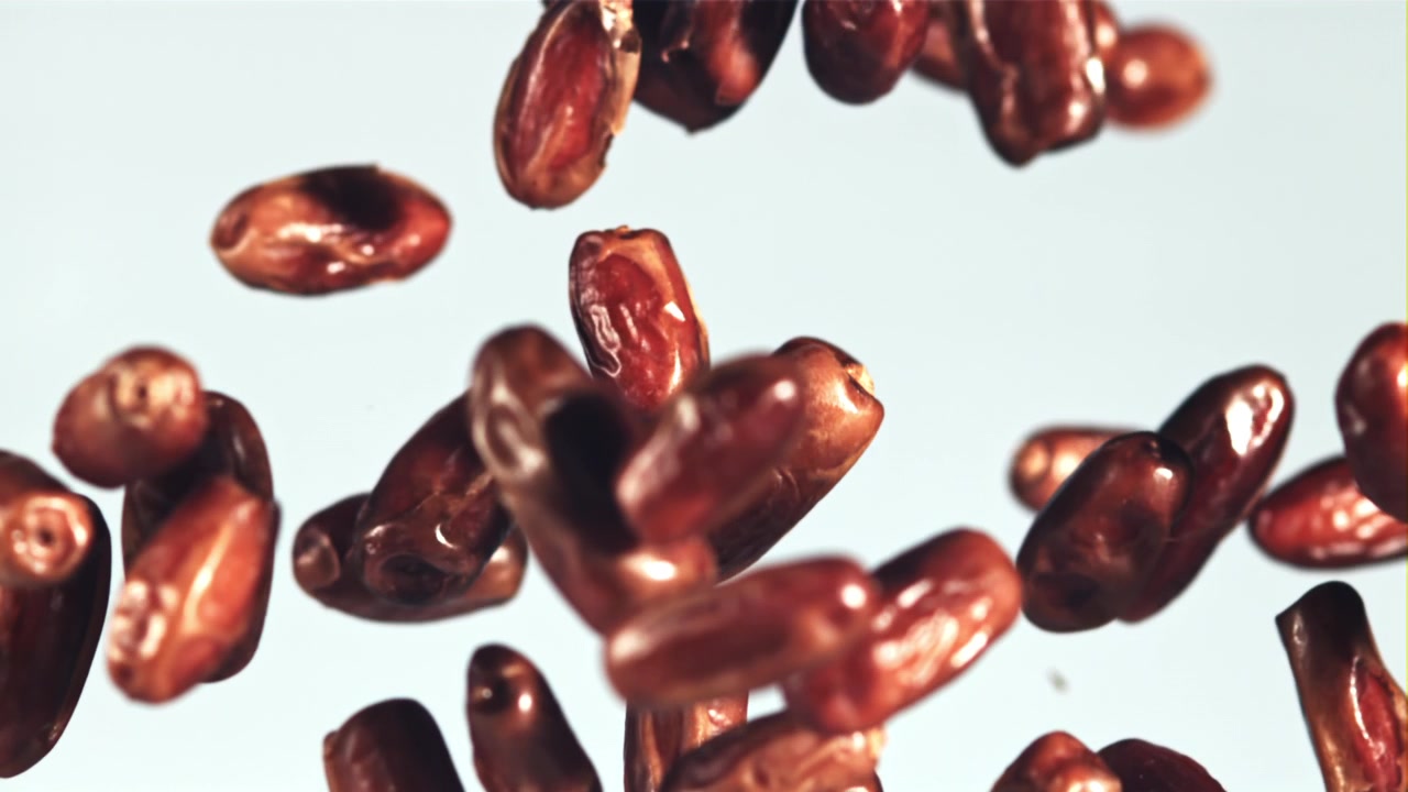Fresh Dates Falling in Slow Motion on a White Background