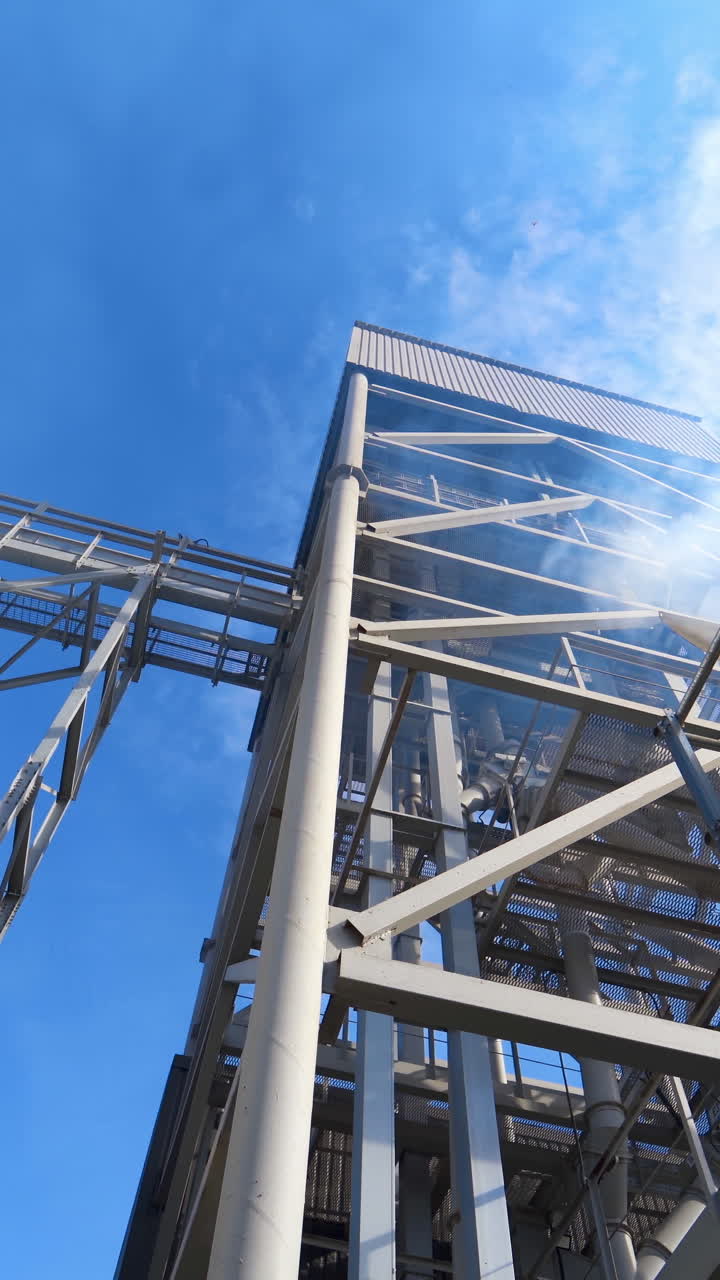 Drying grain on a modern factory. Large grain elevator and smoke from industry. Vapor releases from industrial plant during grain processing. Vertical video