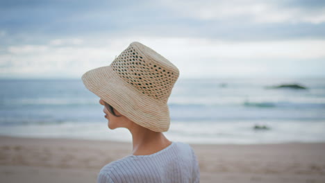 mujer caminando playa nublada vista trasera de primer plano. chica atractiva girando en la orilla