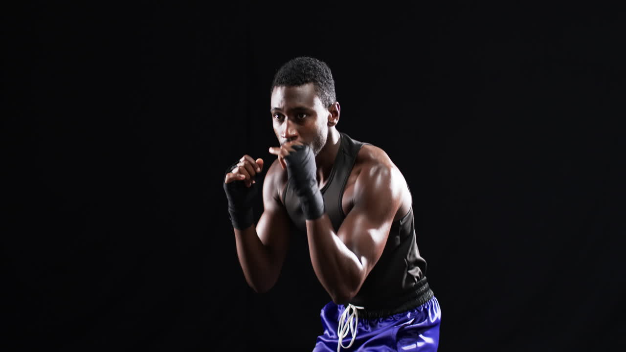 boxeador afroamericano en posición de lucha sobre un fondo negro