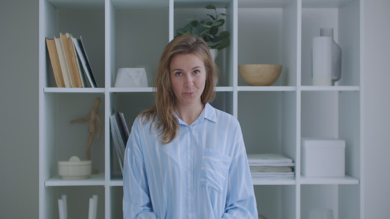 Ung kvinde med krøllet hår taler. Kvinde til jobsamtale. Teenager pige blogger/vlogger laver online videoopkald, optager vlog/blog, taler til kameraet og kigger på webcam indendørs derhjemme.