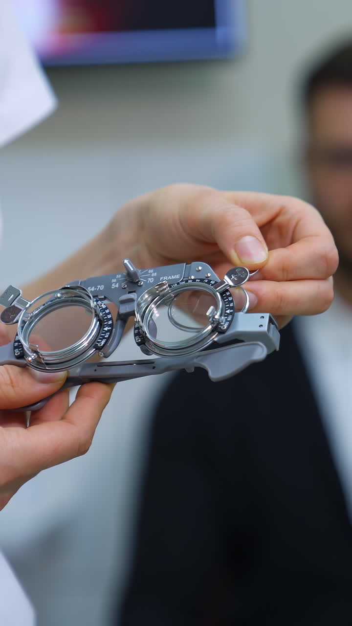 Ophthalmological trial frame and test glasses in woman's hands. Eysight correction. Young man on blurred background. Vertical video