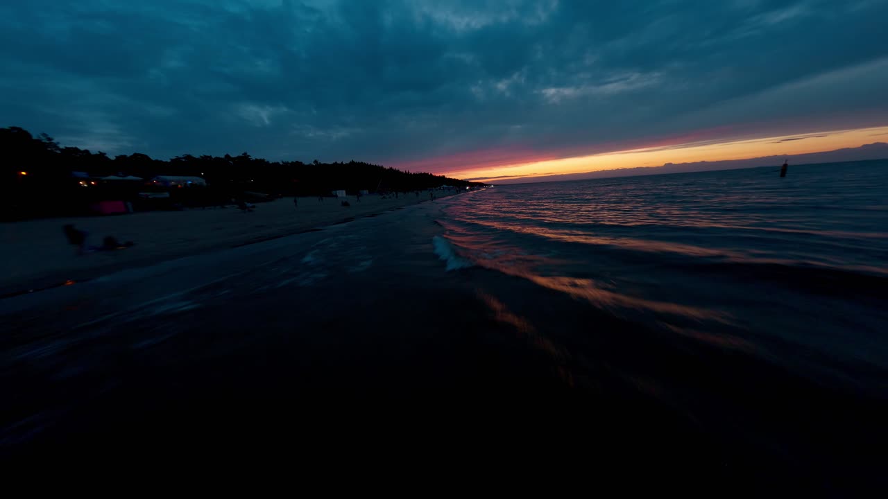 Dron FPV volando rápido sobre las olas del Mar Báltico en Polonia al atardecer