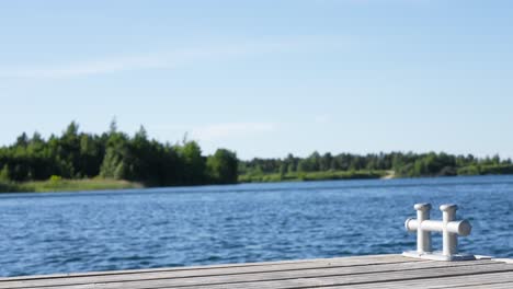 beautiful footage of a boat docking cleat on a wooden boat bridge on a small blue lake with green trees in the background in estonia harjumaa located in europe baltics