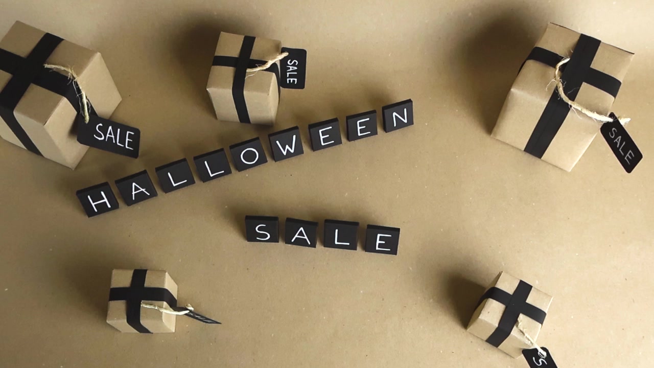 Halloween sale promotional concept showing the text made from black cubes surrounded by gift boxes wrapped in craft paper with black ribbons and tags, viewed from the top down