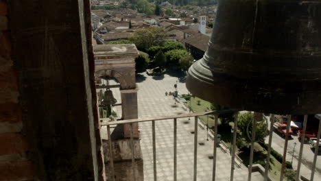 Campanas-De-Iglesia-Montadas-En-Una-Torre-Alta-En-La-Plaza-Pública-De-Un-Pequeño-Pueblo-Mexicano,-Que-Pueden-Ser-Escuchadas-Por-La-Comunidad-Circundante