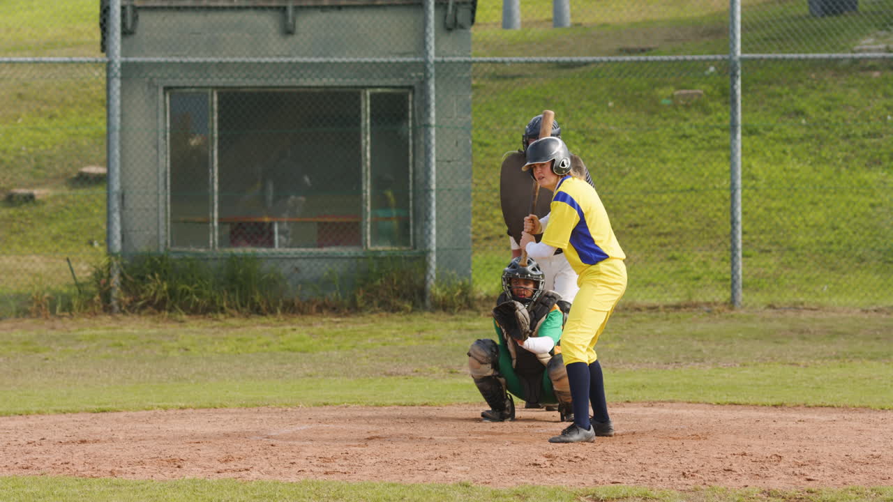 Multiracial female baseball players and male umpire, hitting the ball and running on a pitch