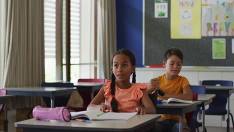 Portrait-of-happy-mixed-race-girl-sitting-in-wheelchair-raising-hand-to-answer-questions