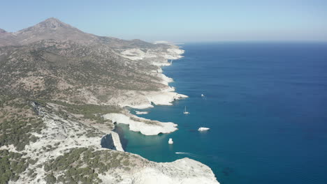 Aerial-Wide-Dolly-forward-of-Shoreline-with-White-Rocks-and-Boats-in-the-Ocean