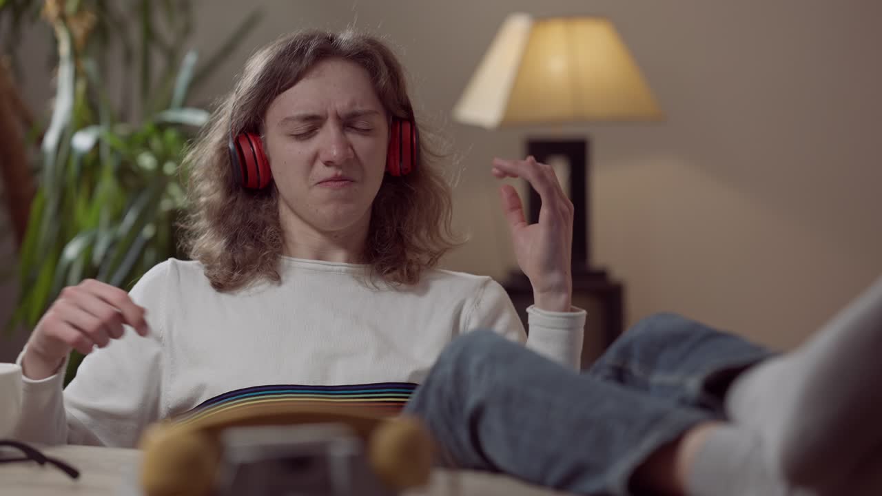 Portrait of happy relaxed young man in headphones with closed eyes listening to music imitating guitar playing. Carefree Caucasian 1980s 1990s guy enjoying playlist at home indoors. Leisure vintage