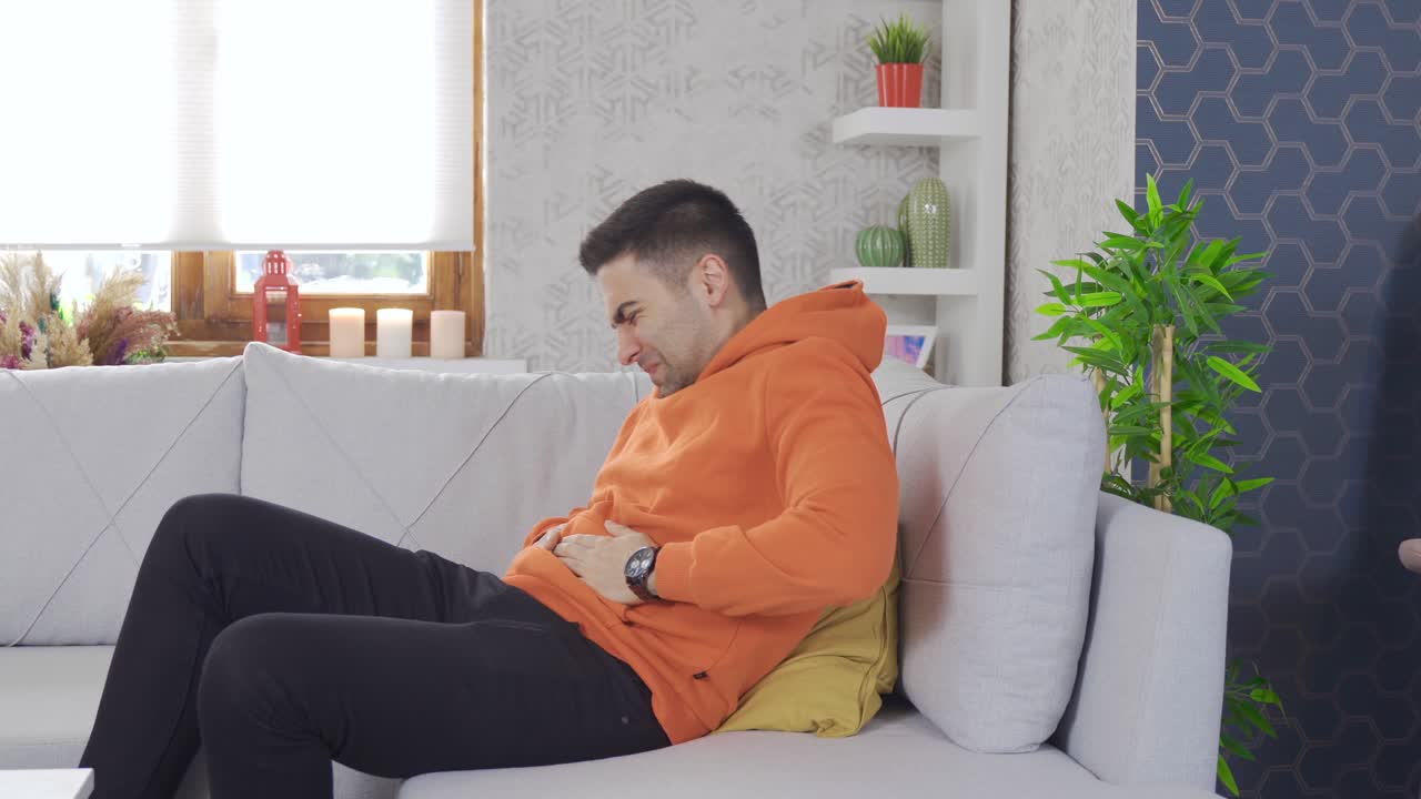 Young man with stomach ache at home.