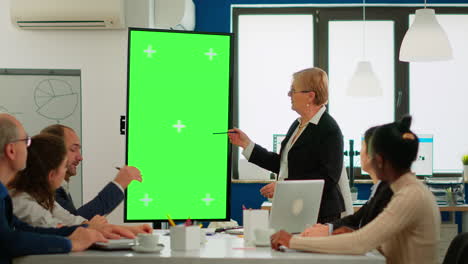 líder del equipo de pie en la mesa de reunión analizando las estadísticas financieras, mirando la pantalla verde