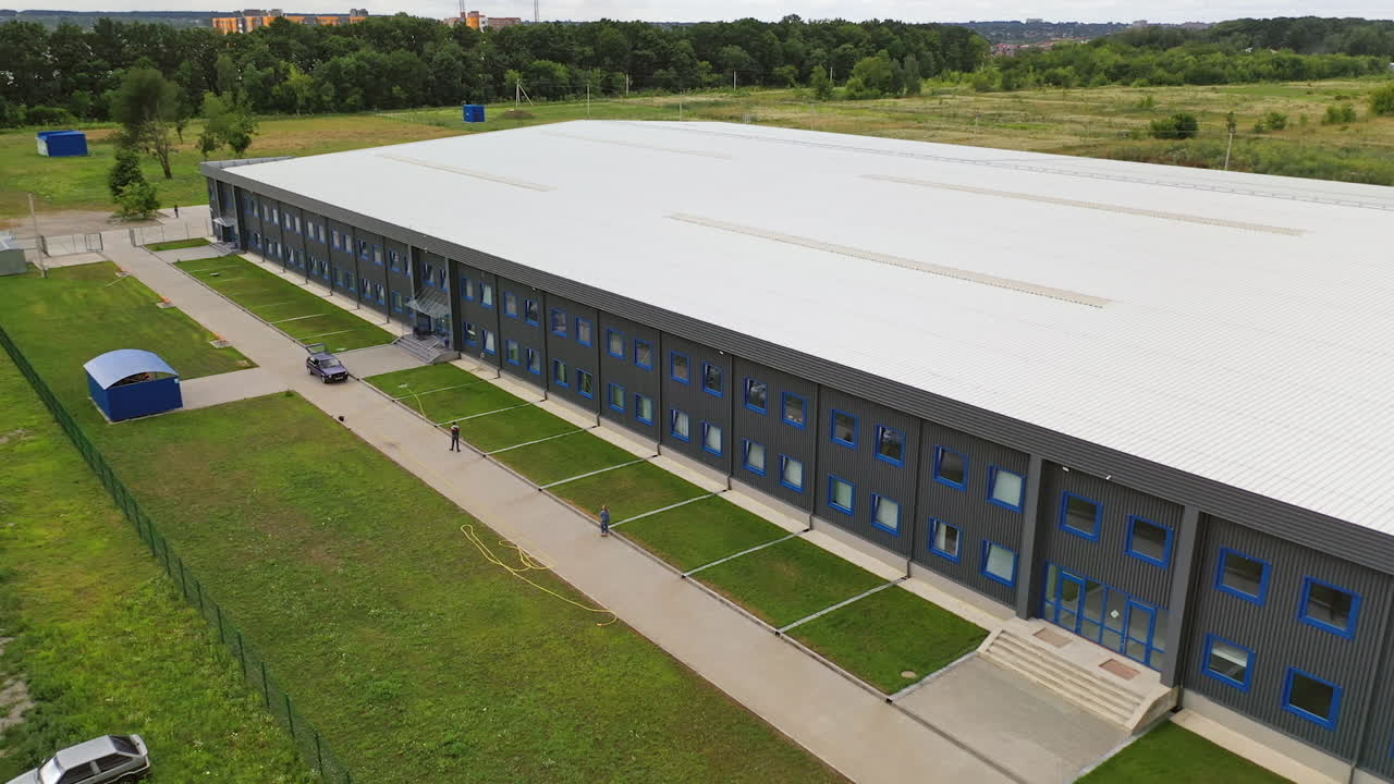 Facade of a modern two-storey building. Industrial plant outdoors. Aerial panorama of beautiful manufacturing with car parking. Summer time.