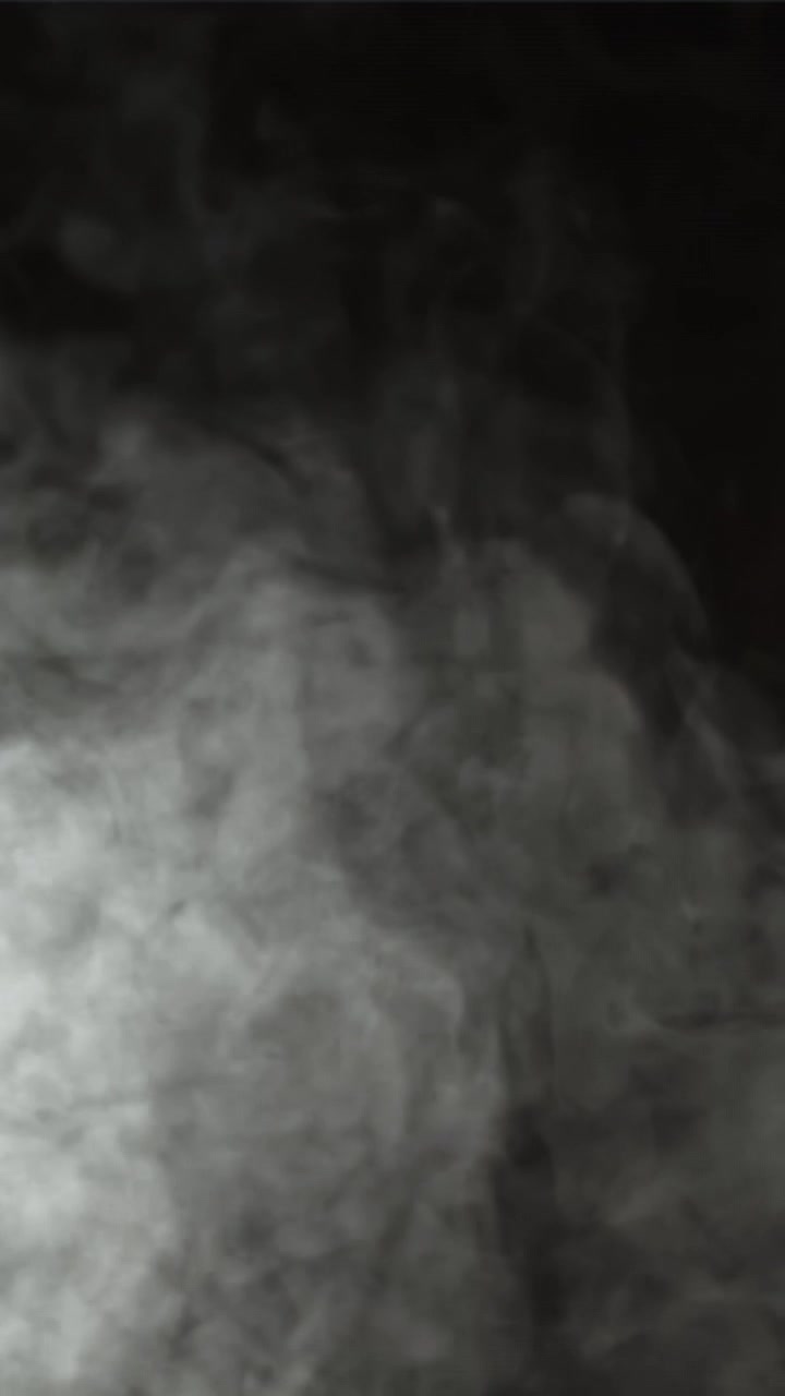 Fumo bianco vorticoso che sale su sfondo nero