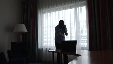 shot of an angry man checking his laptop while talking on mobile phone yelling on business problems