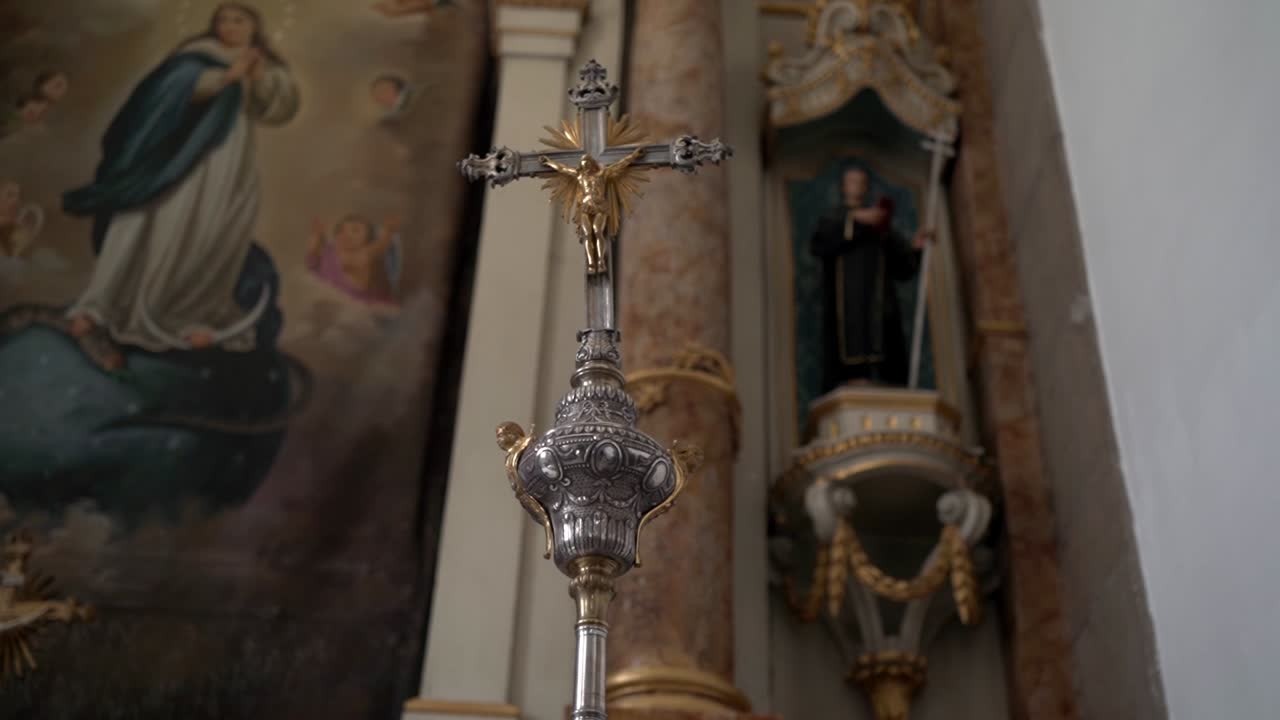 Detail ozdobného krucifixu s obrazy a sochami uvnitř kostela