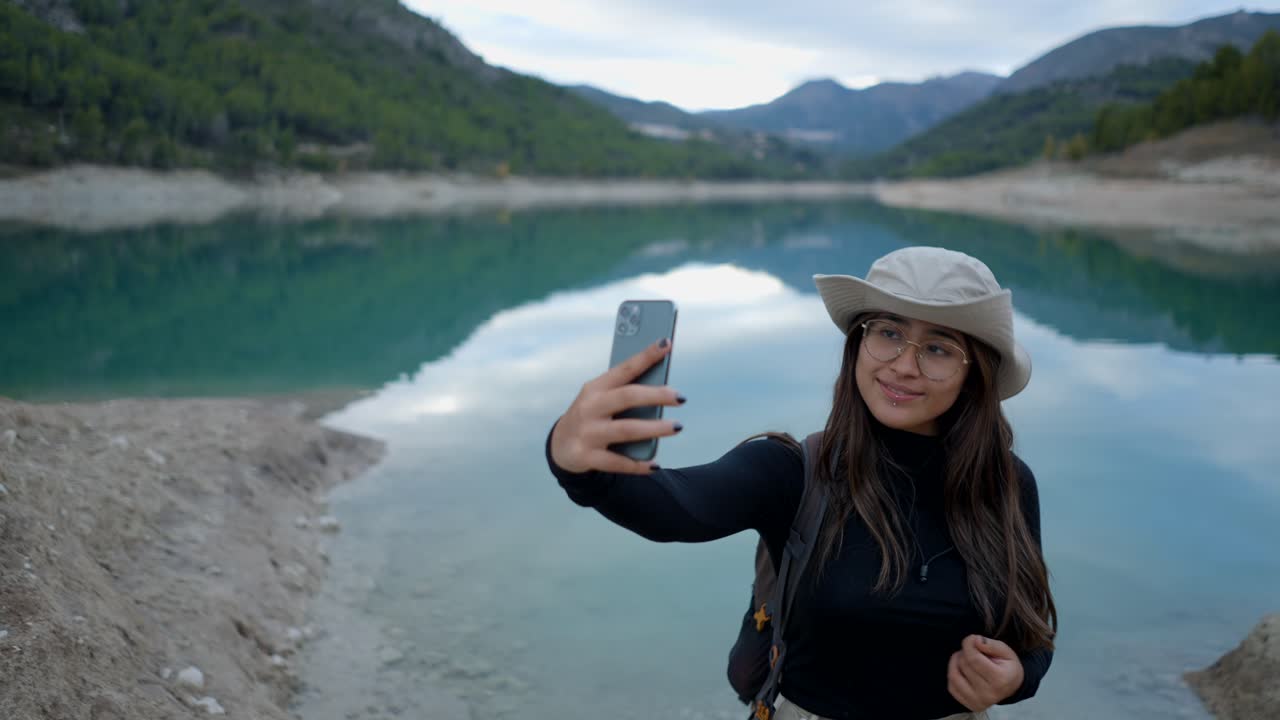 una mujer tomando una selfie junto a un lago.