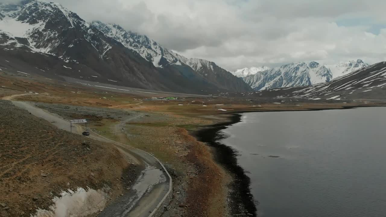 Luchtopname van een SUV die off-road rijdt naast het Shandurmeer in Pakistan. Dolly naar voren.
