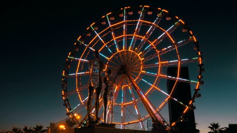 Statue of Ali and Nino on a background Ferris wheel at night on the embankment of Batumi, Georgia