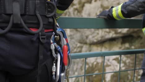 closeup of firefighter wearing belt with safety carabiners, standing on the bridge