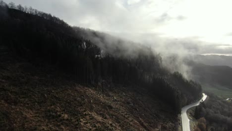 Vista-Aérea-De-La-Niebla-Otoñal-Matutina-Sobre-Colinas-Empinadas,-Bosques-Y-Caminos-Rurales